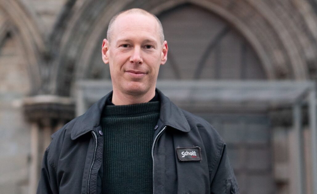 En mann står utenfor midtportalen på Nidarosdomens vestfront.