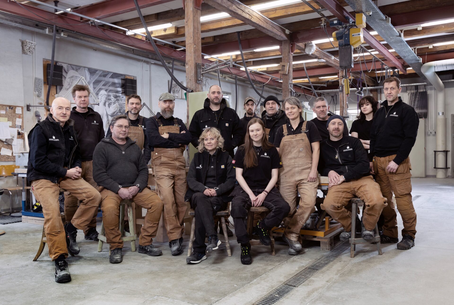 En gruppe håndverkere står oppstilt i et steinhuggerverksted.