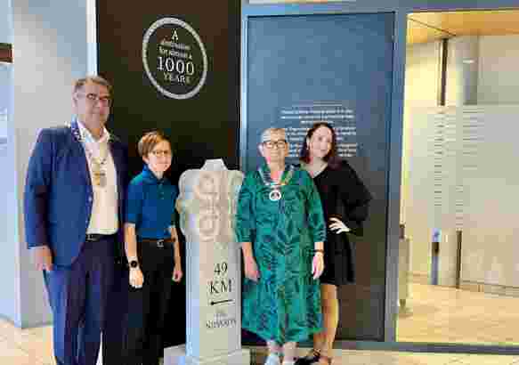 To ordførere og to damer står ved en milestein