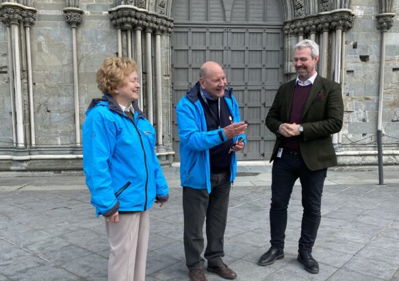 Et eldre par står utenfor Nidarosdomen og snakker med en mann i dress.