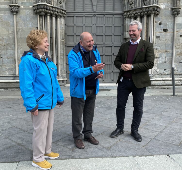 Et eldre par står utenfor Nidarosdomen og snakker med en mann i dress. Et eldre par står utenfor Nidarosdomen og snakker med en mann i dress.