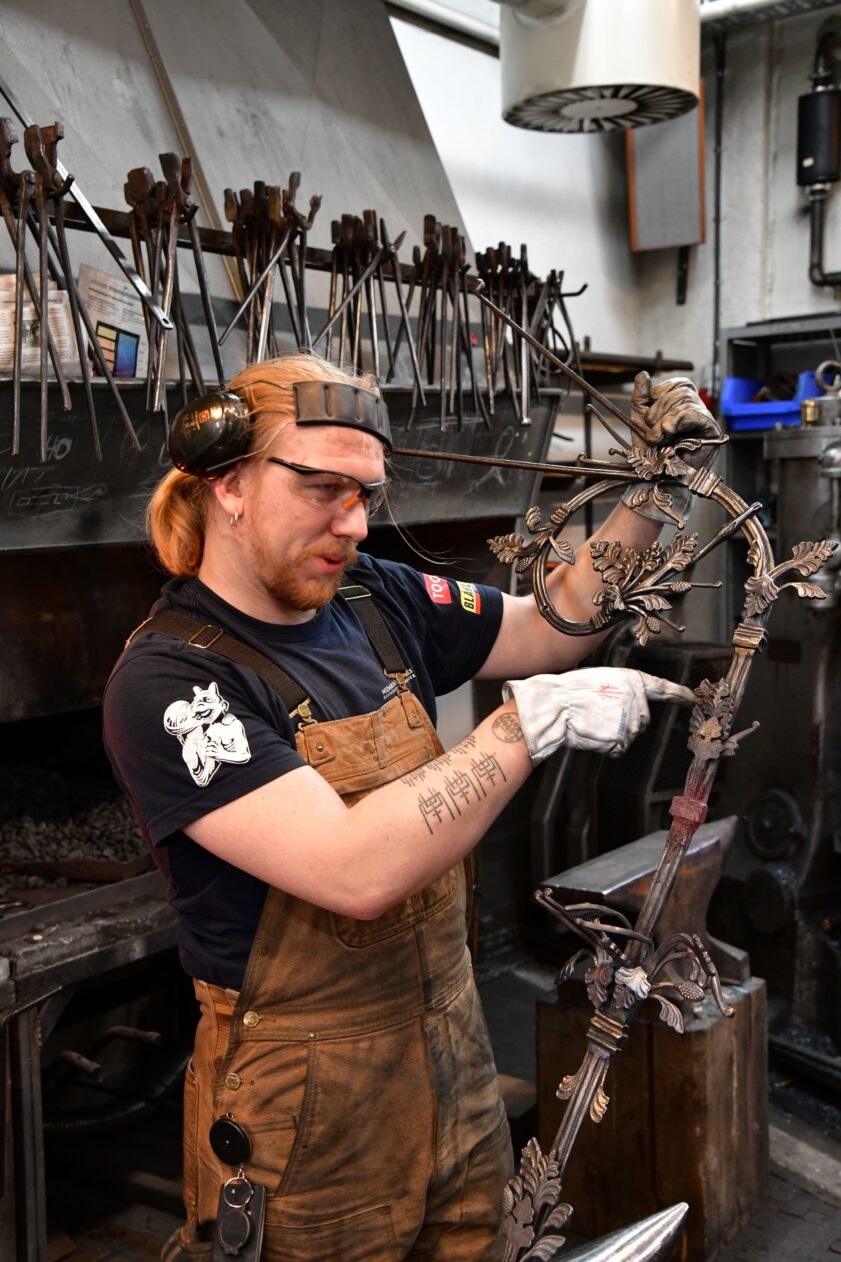 En smed jobber med en stor smijernsdekorasjon.