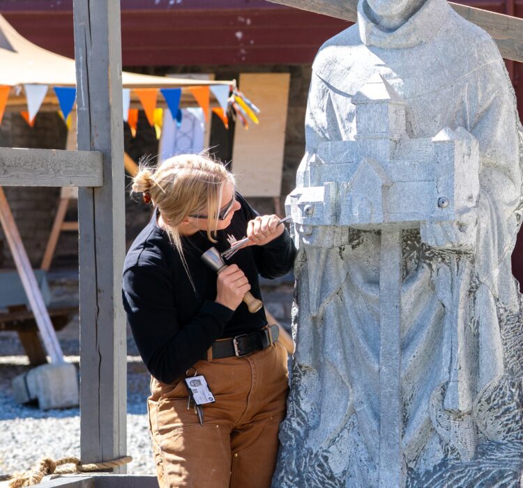 Kvinne hugger på en skulptur i stein.