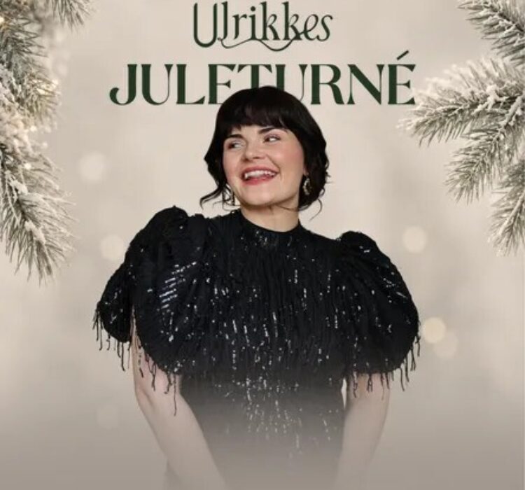 Urbikkes Julestjerne: kvinne i svart glitrende kjole smilende når kameraet tas, bakgrunnen har bjørkefrø og julepynt. Urbikkes Julestjerne: kvinne i svart glitrende kjole smilende når kameraet tas, bakgrunnen har bjørkefrø og julepynt.