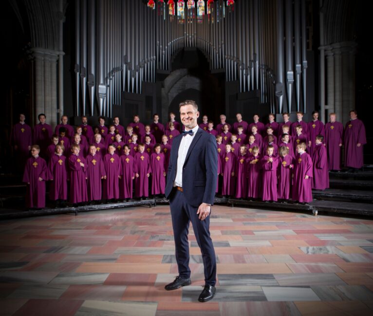 En mann i dress står foran et stort guttekor